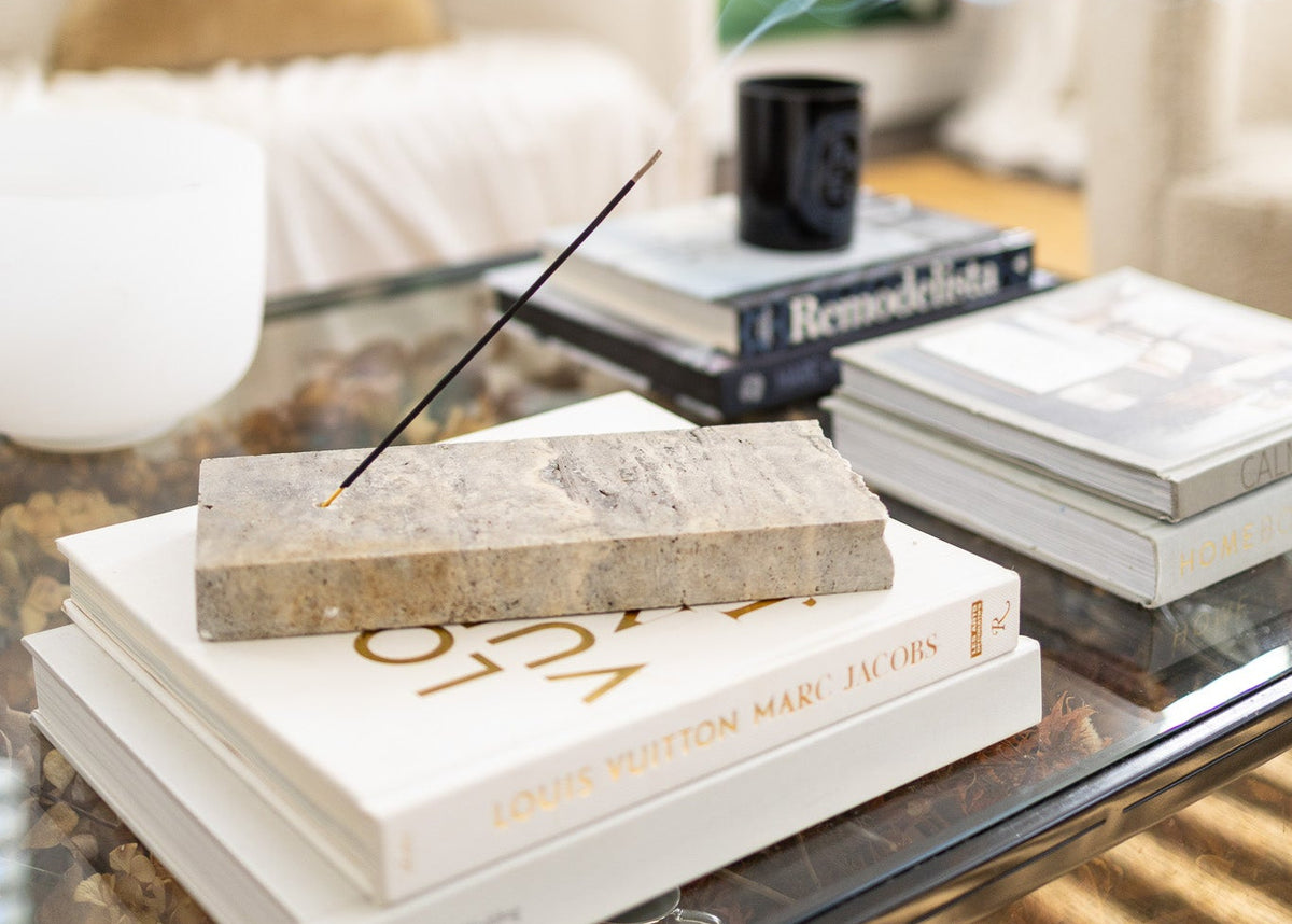 Decorative books on a glass coffee table with a candle and a blurred background