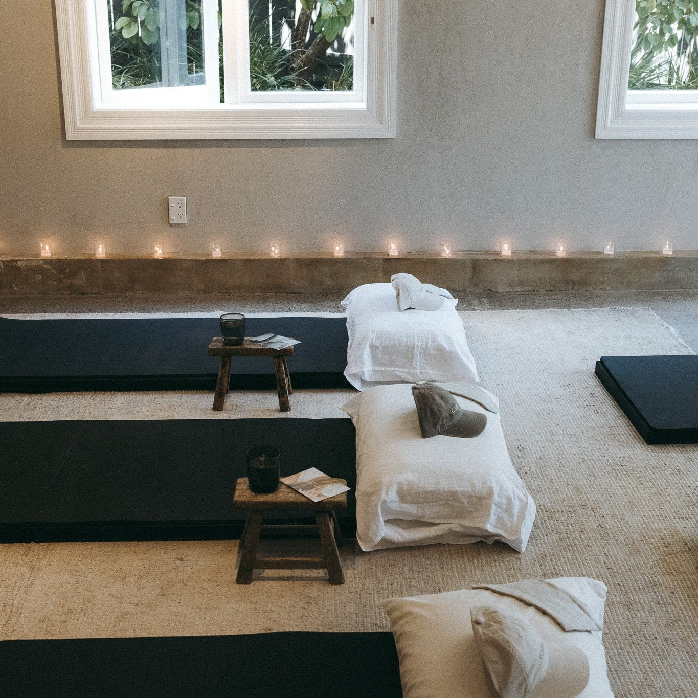 Jin Shin Jyutsu Self Help Meditation room with black mats, white cushions, and small tables.